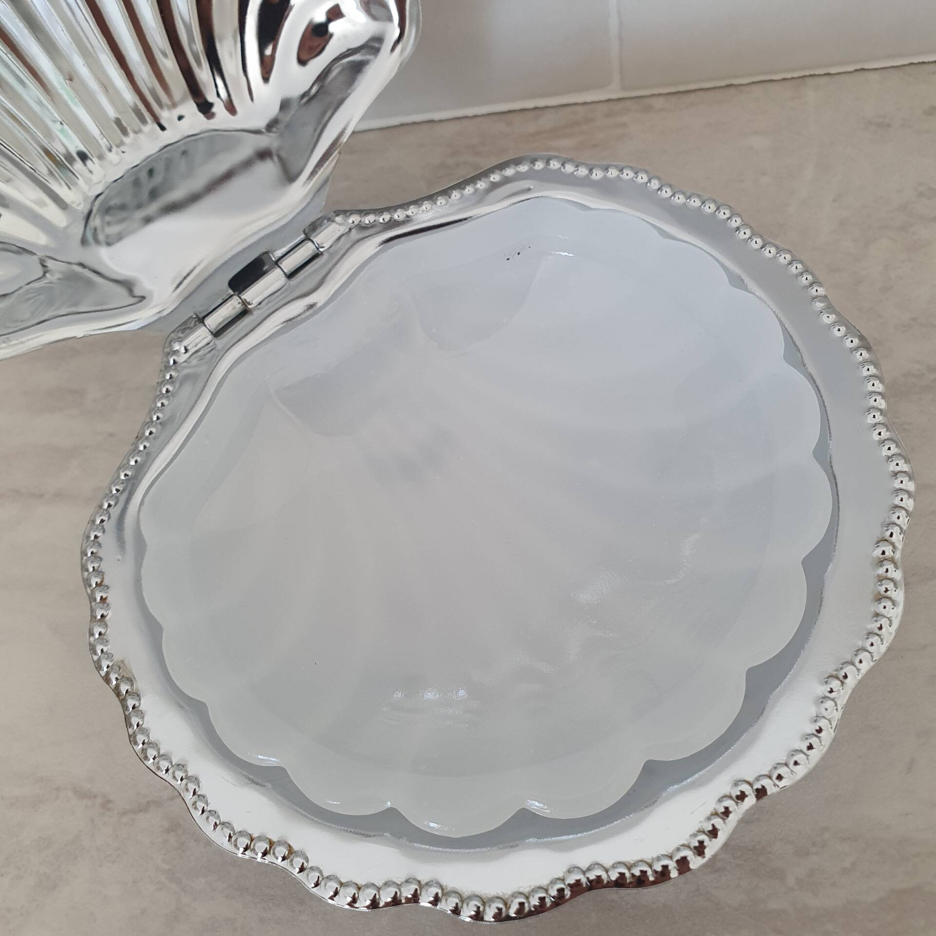 Scallop shell butter dish in stainless steel with its white glass saucer.