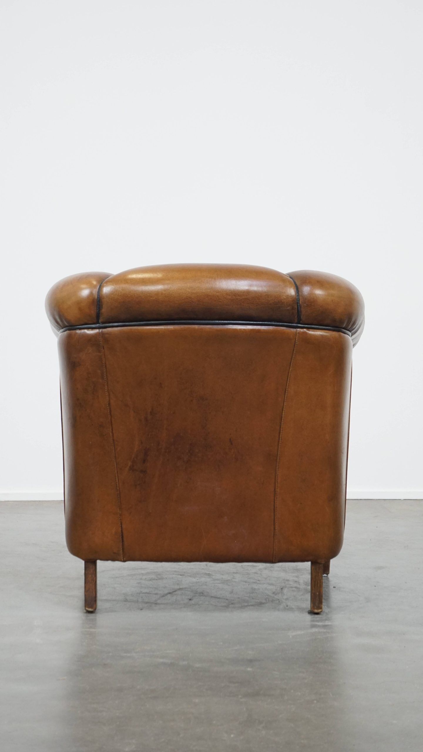 Unique vintage cognac-coloured leather club armchair with black piping
