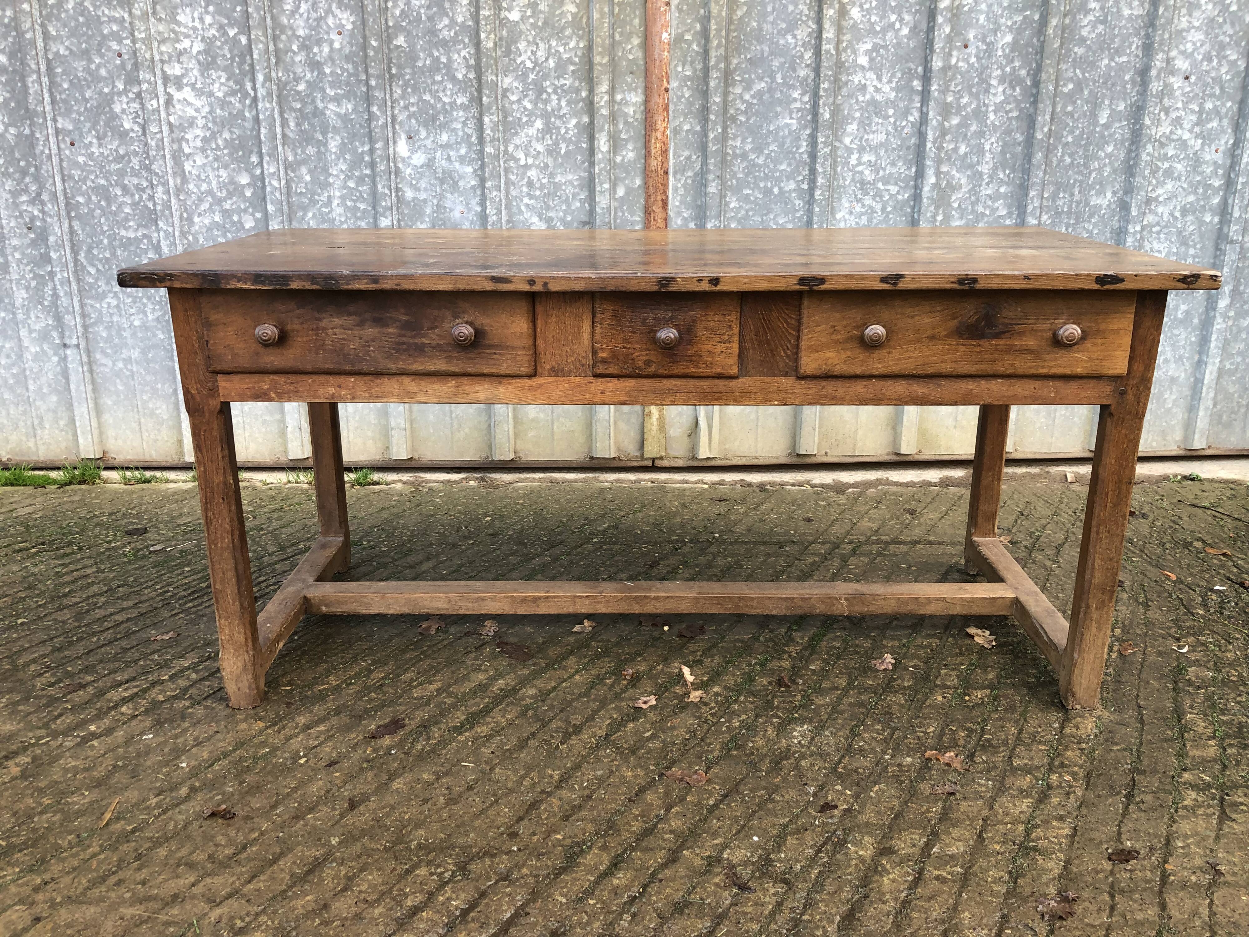 Old chestnut table with 3 front drawers and a cat bar.