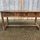Old chestnut table with 3 front drawers and a cat bar.