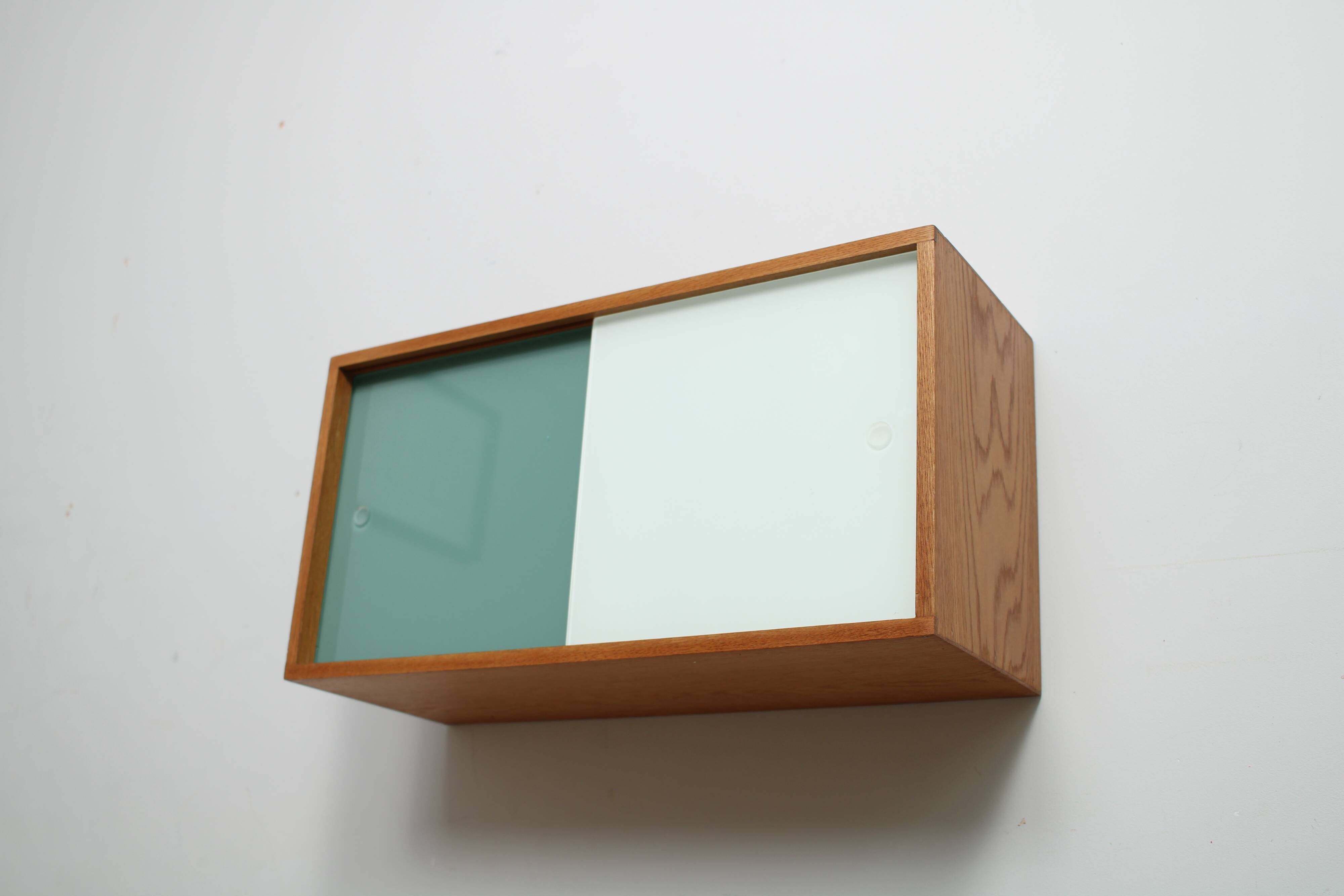 A vintage mid-century wall hung oak cabinet, green & white glass doors