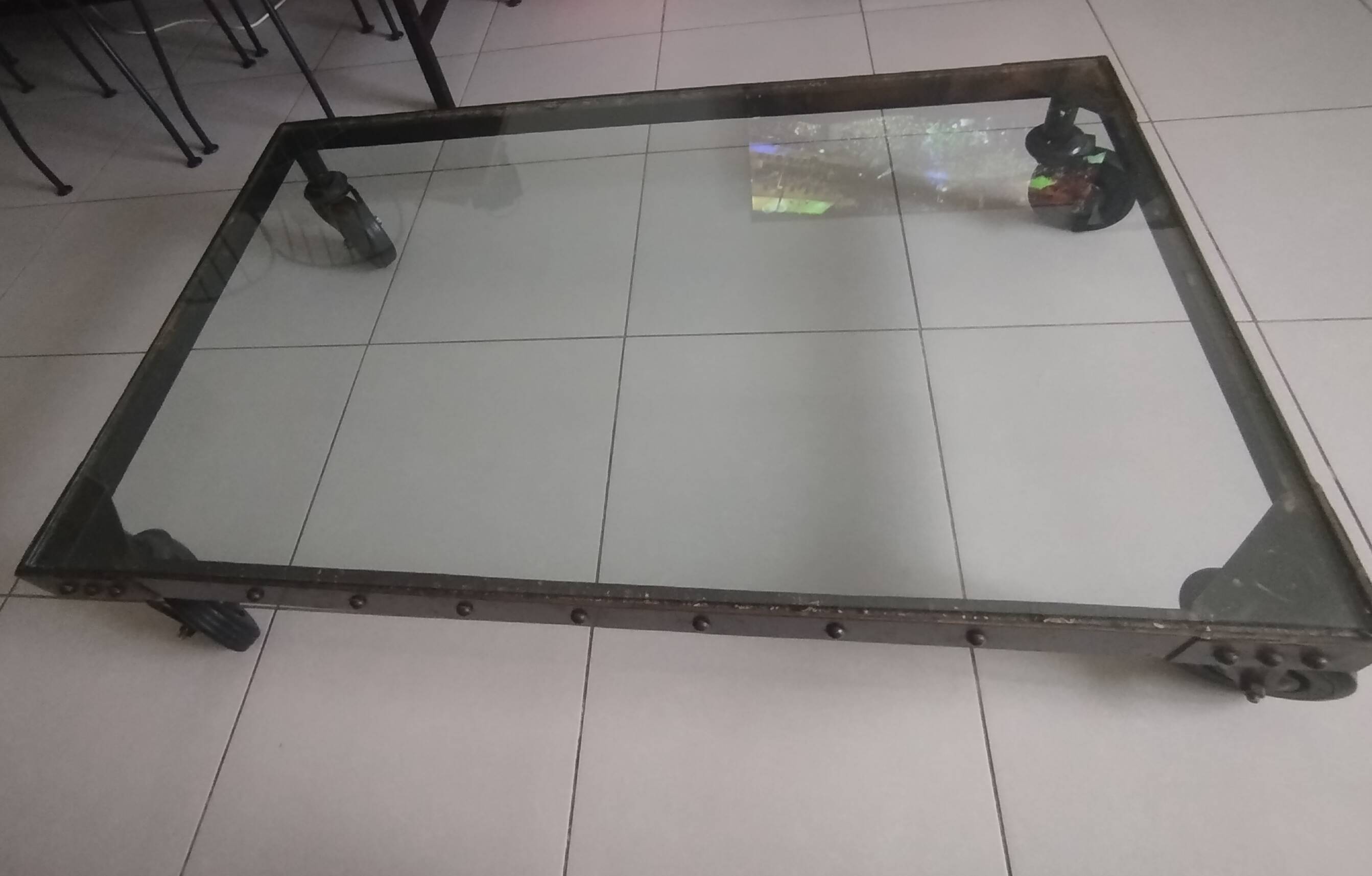 Industrial coffee table in solid metal with a glass top.