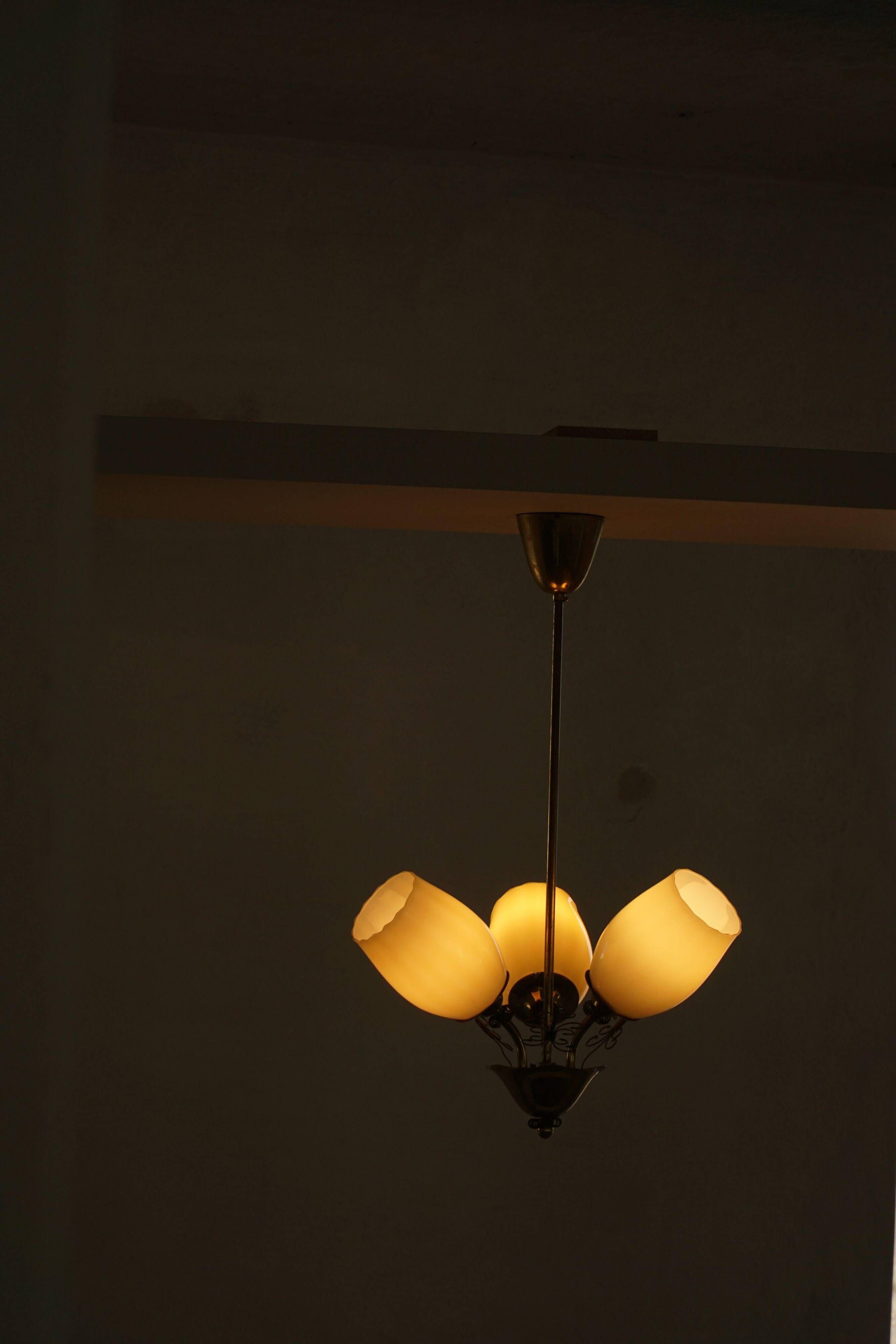 Paavo Tynell for Idman Oy, three-branch chandelier in brass and glass, mid-century, 1940s.