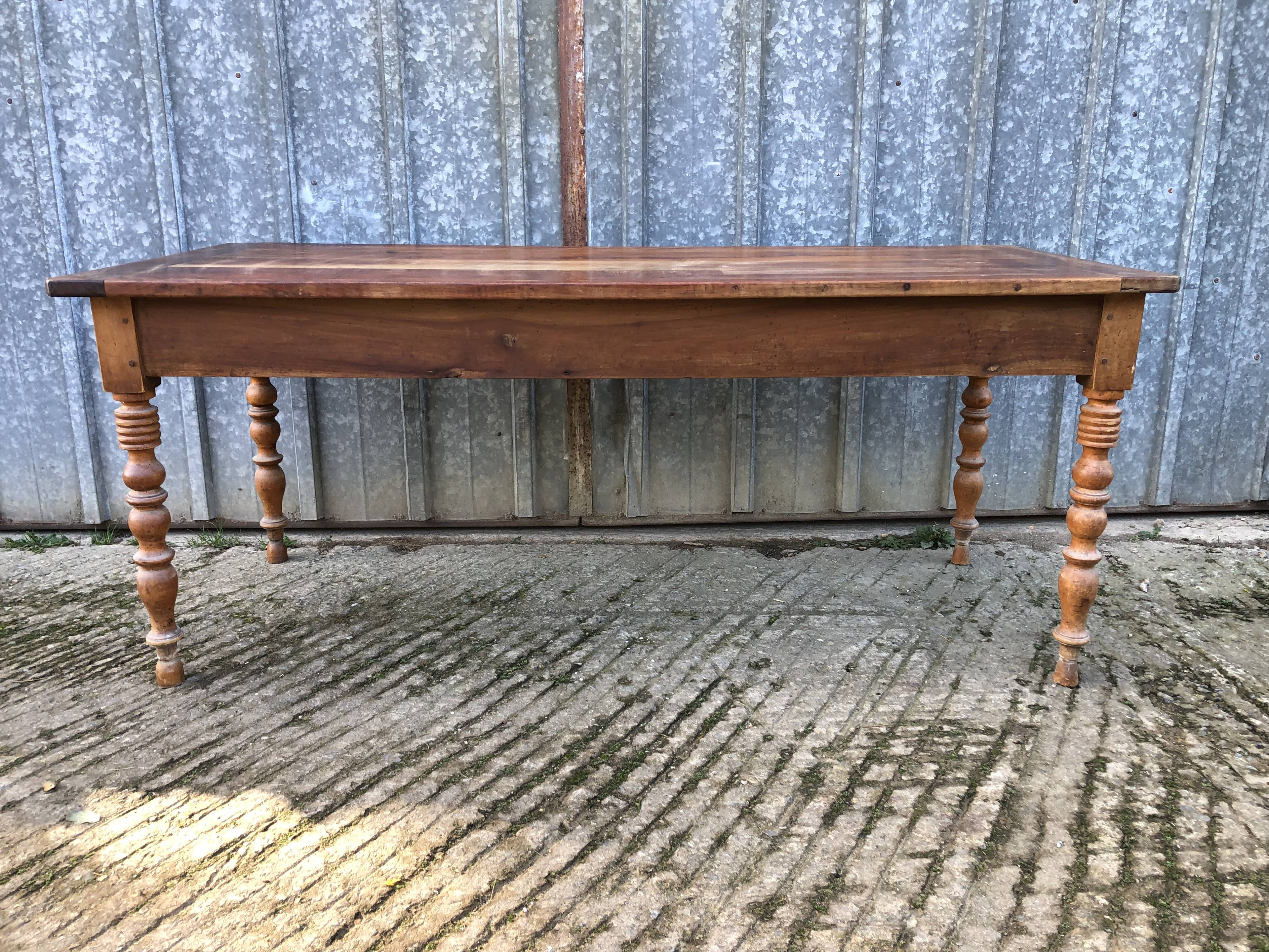 Antique farmhouse table in solid cherry wood with turned legs.
