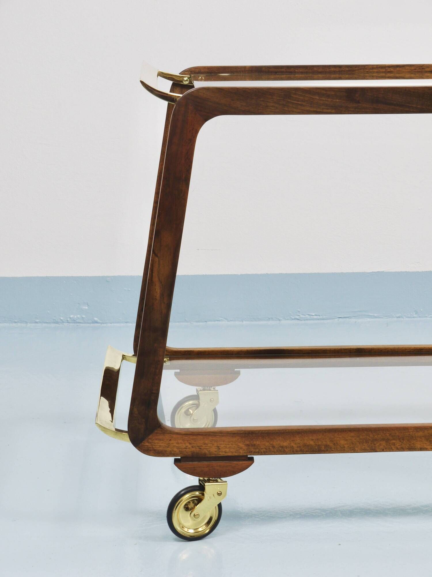 May include: A mid-century modern bar cart with a dark wood frame and two c