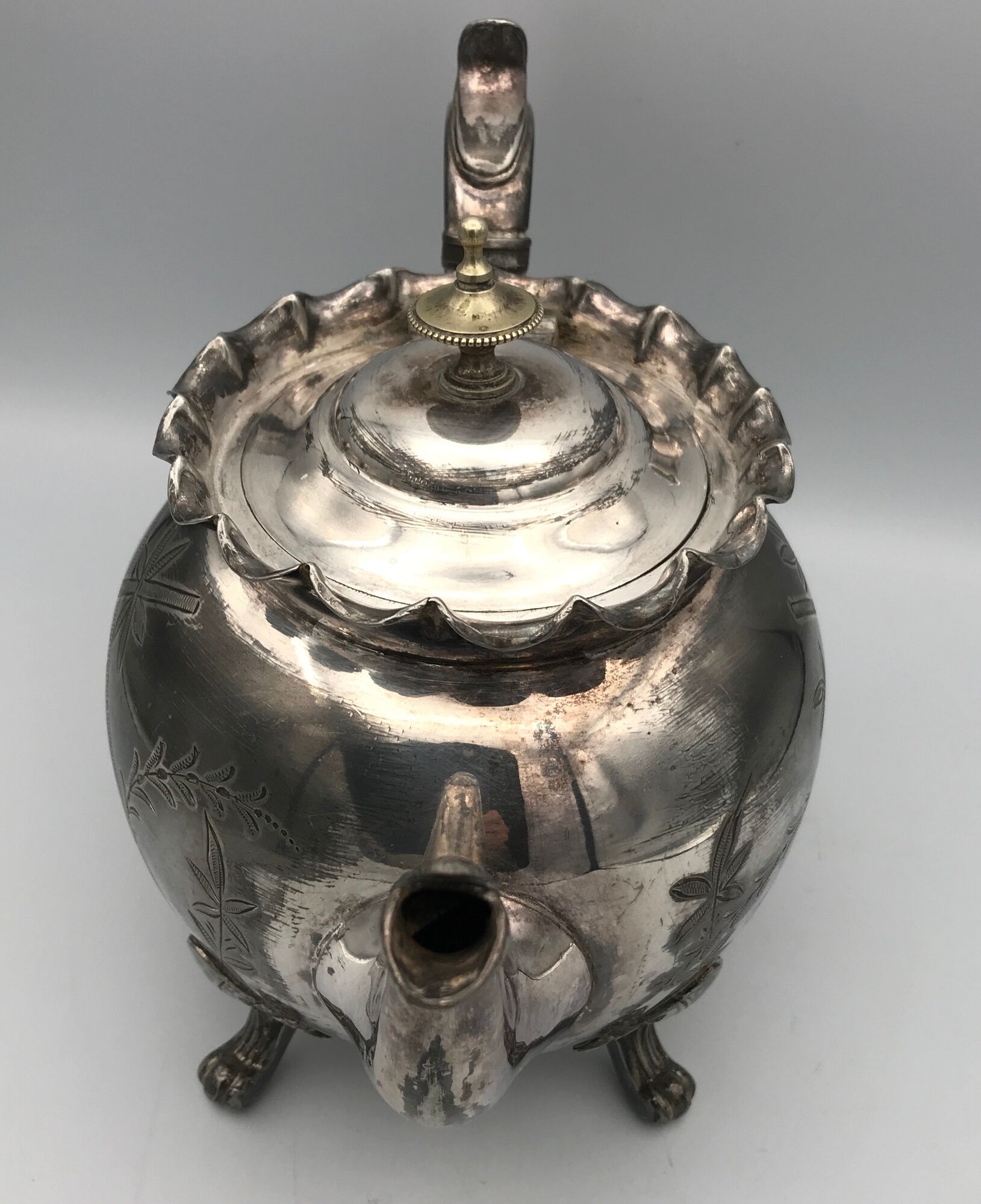 Old teapot pourer in silver metal decorated with foliage and butterflies