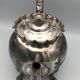 Old teapot pourer in silver metal decorated with foliage and butterflies