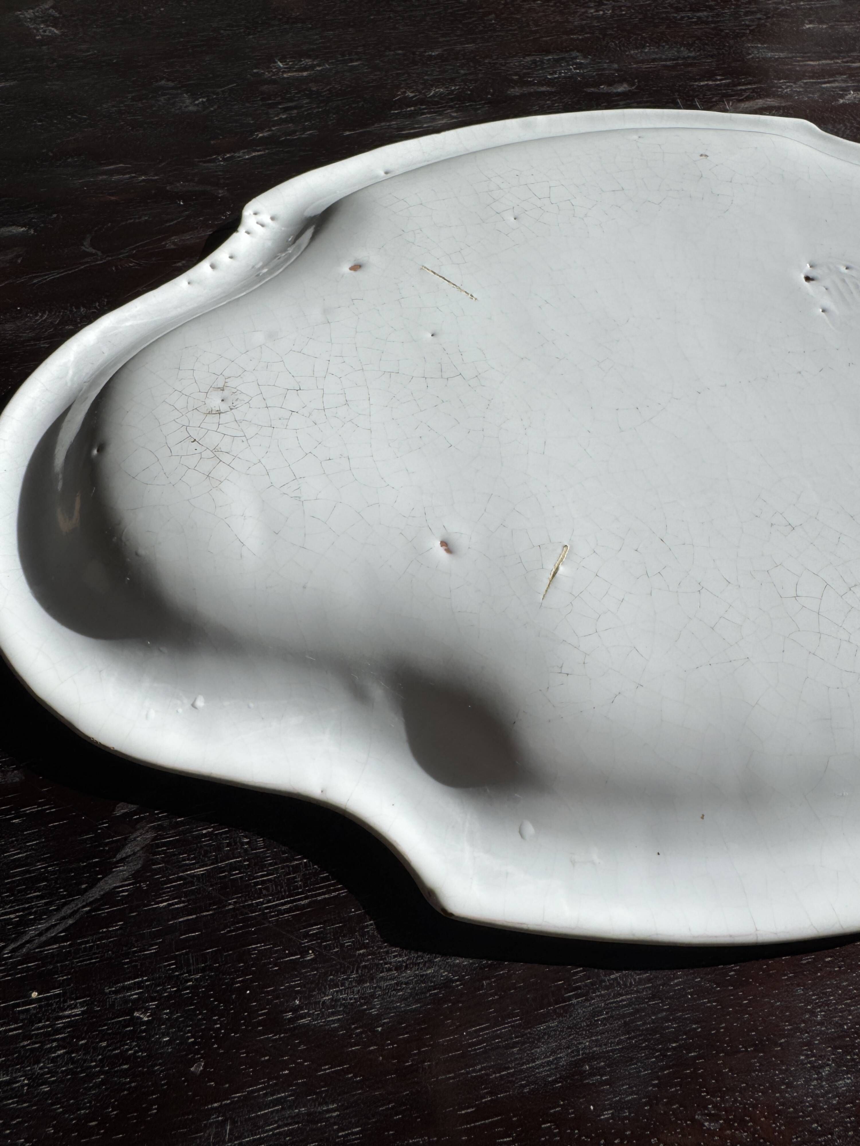Antique oval-shaped white crackled faience plate with a scalloped edge.