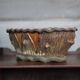 Terracotta planter in a brutalist style resembling a tree trunk, pot cover, countryside.
