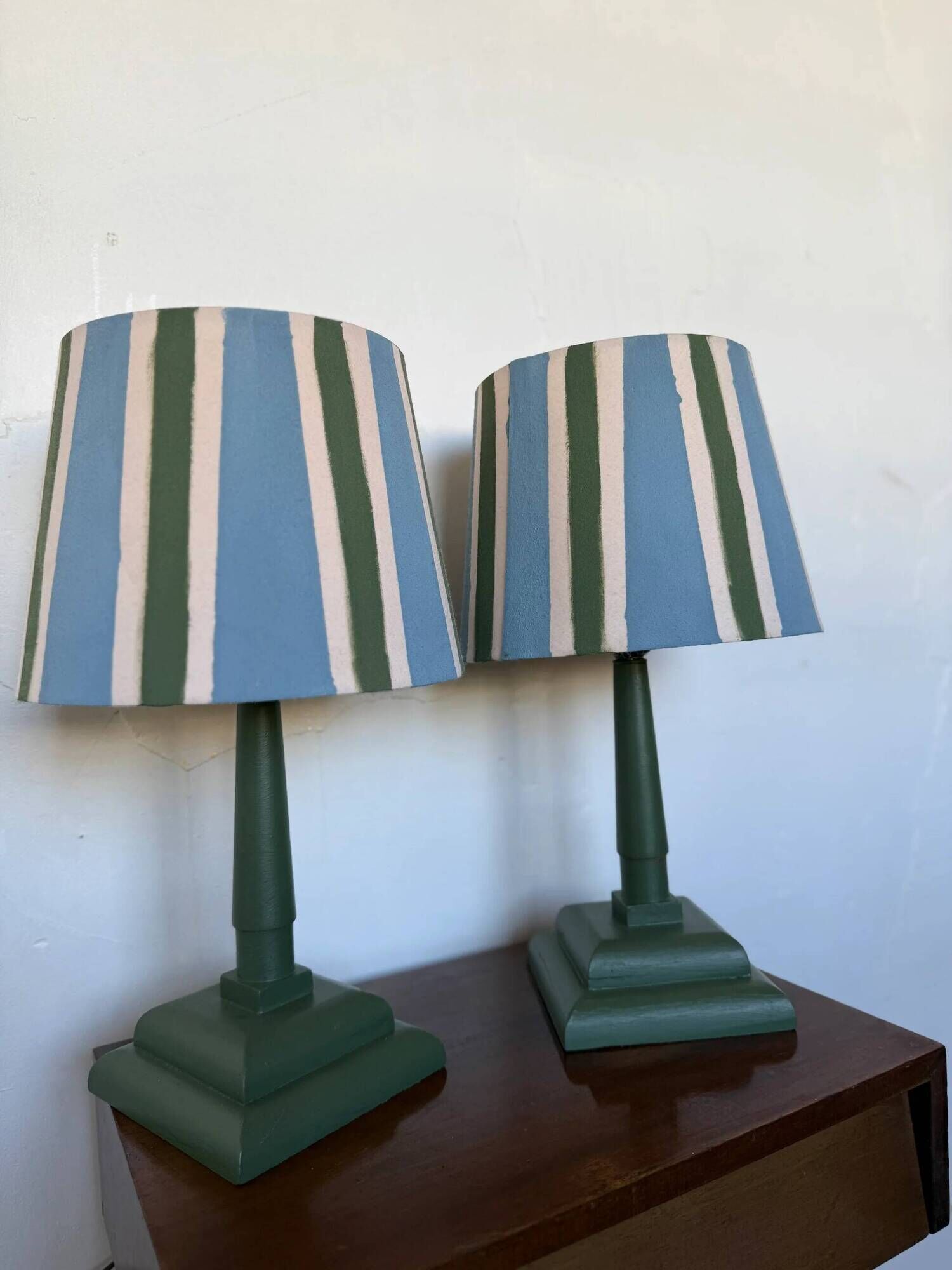 Pair of vintage wooden lamps with their striped beige, blue, and green shades.