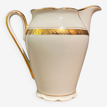 Porcelain milk jug with gold decoration on a white background