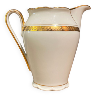 Porcelain milk jug with gold decoration on a white background