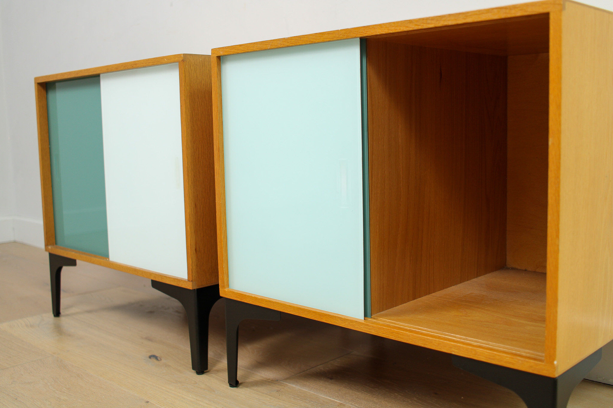 A pair of vintage mid-century bedside tables with glass sliding doors