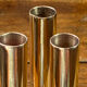 Set of candlesticks and tubular vases in solid brass.