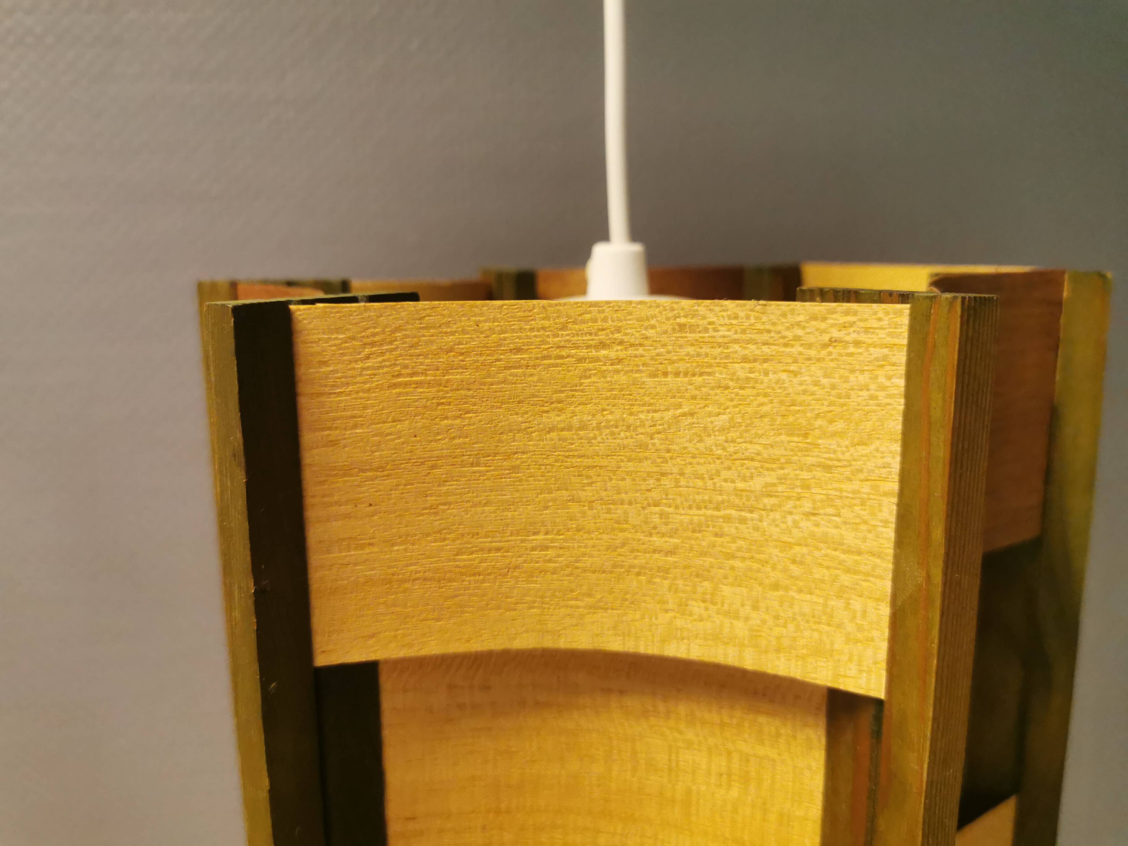Older lamp in wood veneer, partially painted in green colour.