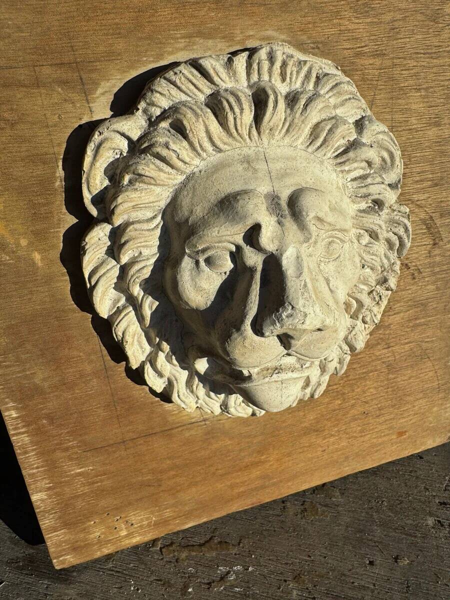 Off-white plaster lion head relief on natural wood panel — Walter De Buck, classical decorative sculpture