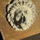 Off-white plaster lion head relief on natural wood panel — Walter De Buck, classical decorative sculpture