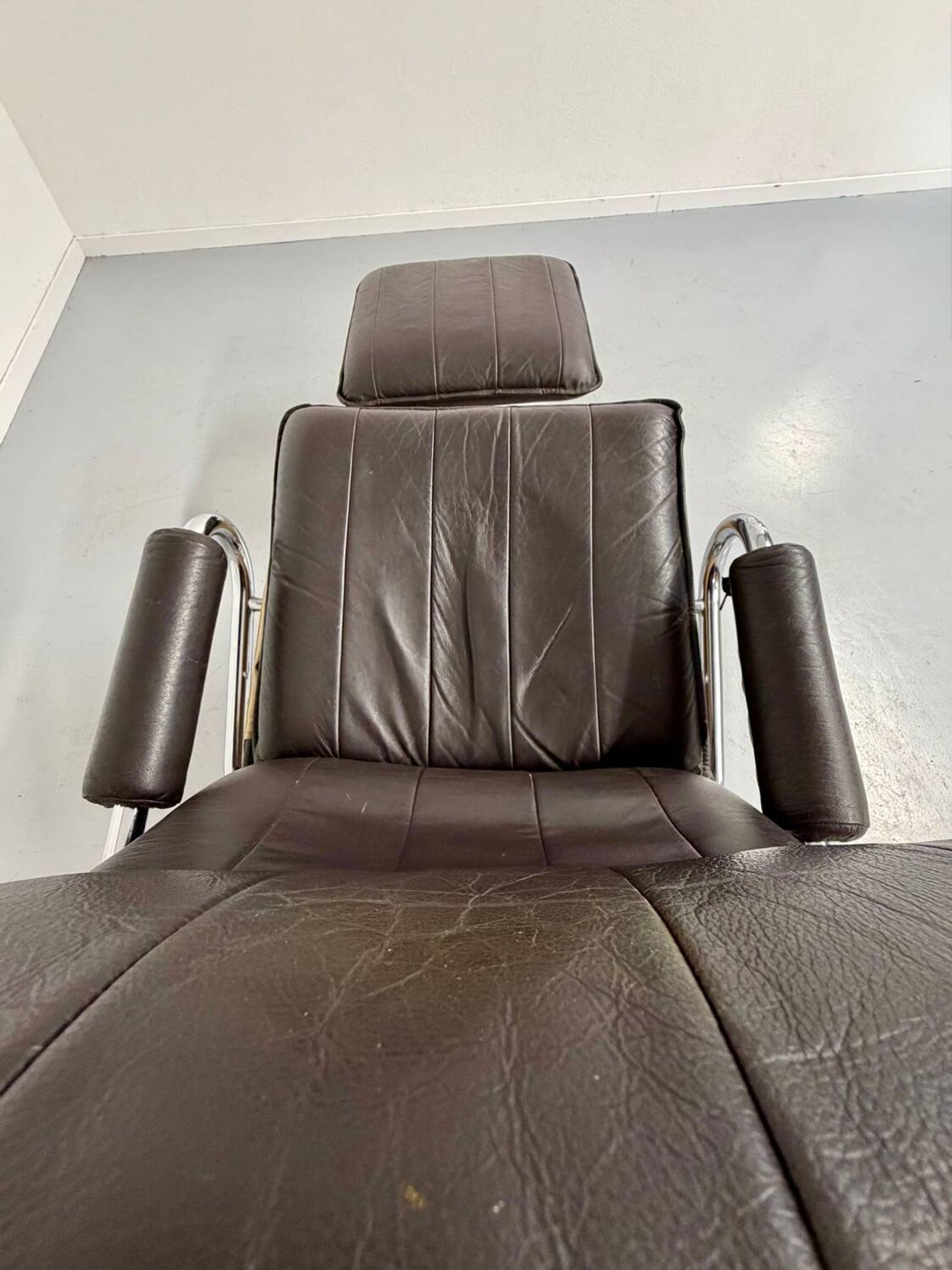 Vintage leather reclining armchair and its 1970s designer ottoman.