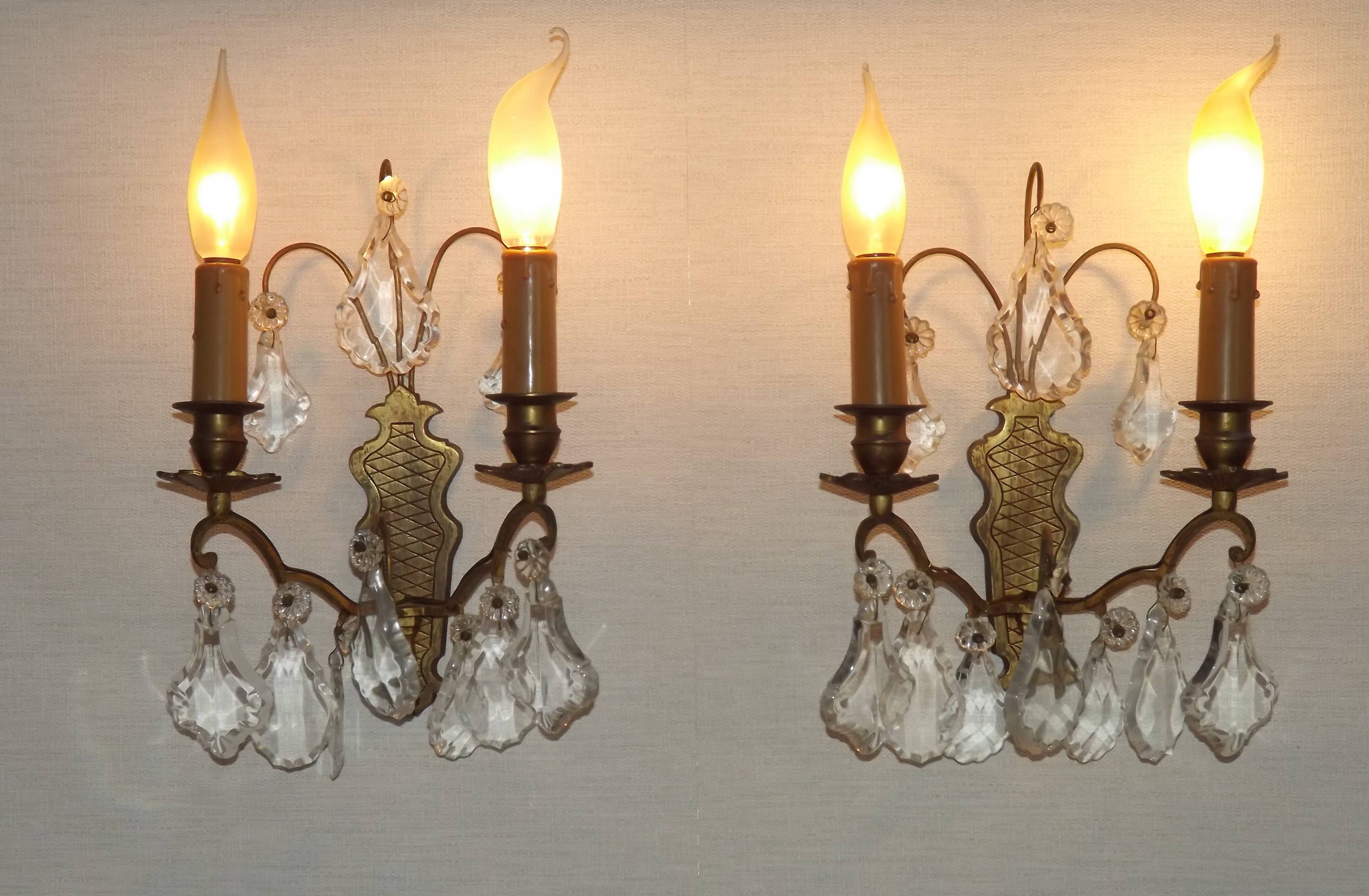 Pair of French antique brass double wall lights with assorted crystals.