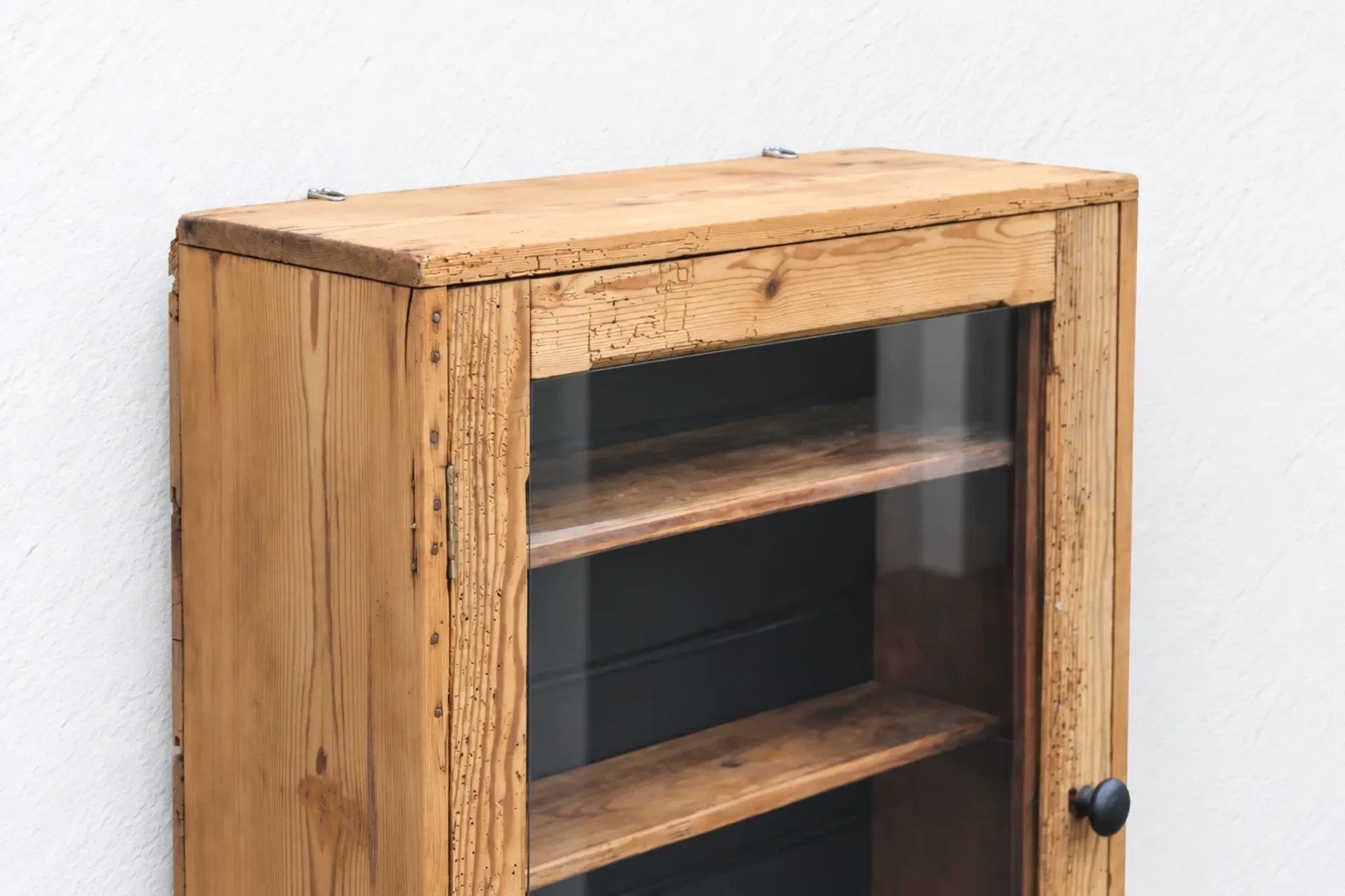 Antique wall display cabinet in natural wood and black – small glass-fronted collector's piece.