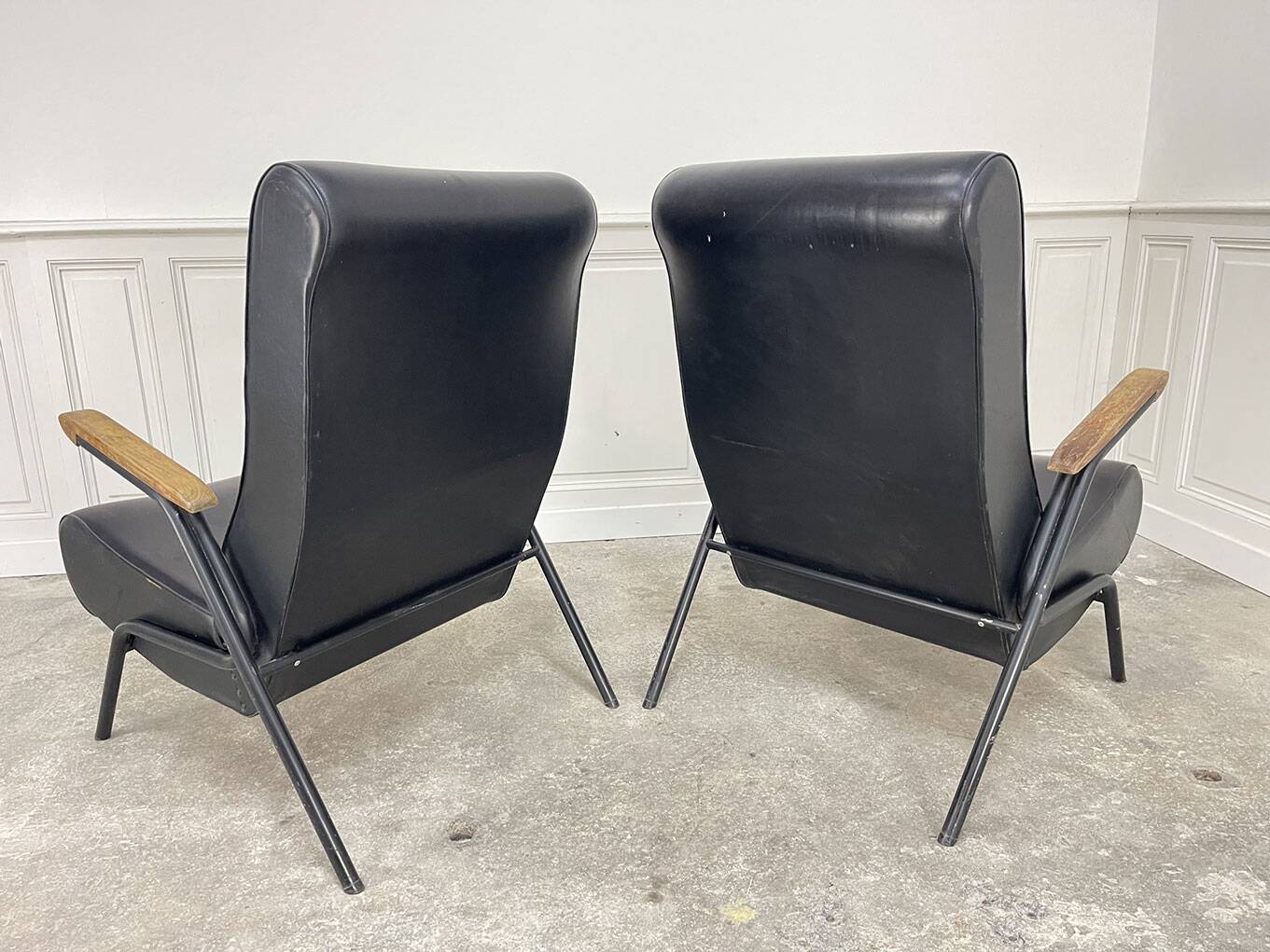 A pair of vintage armchairs in black faux leather.