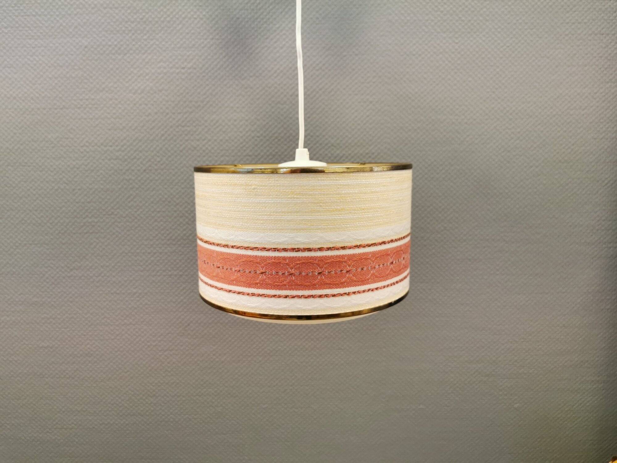 Hanging lamp with brass-coloured details, made of fabric with intact plastic bottom grille.