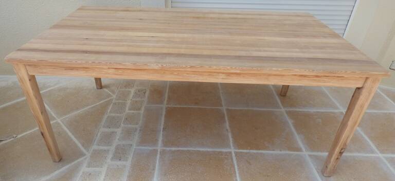 Large natural wood table with rectangular top supported by legs