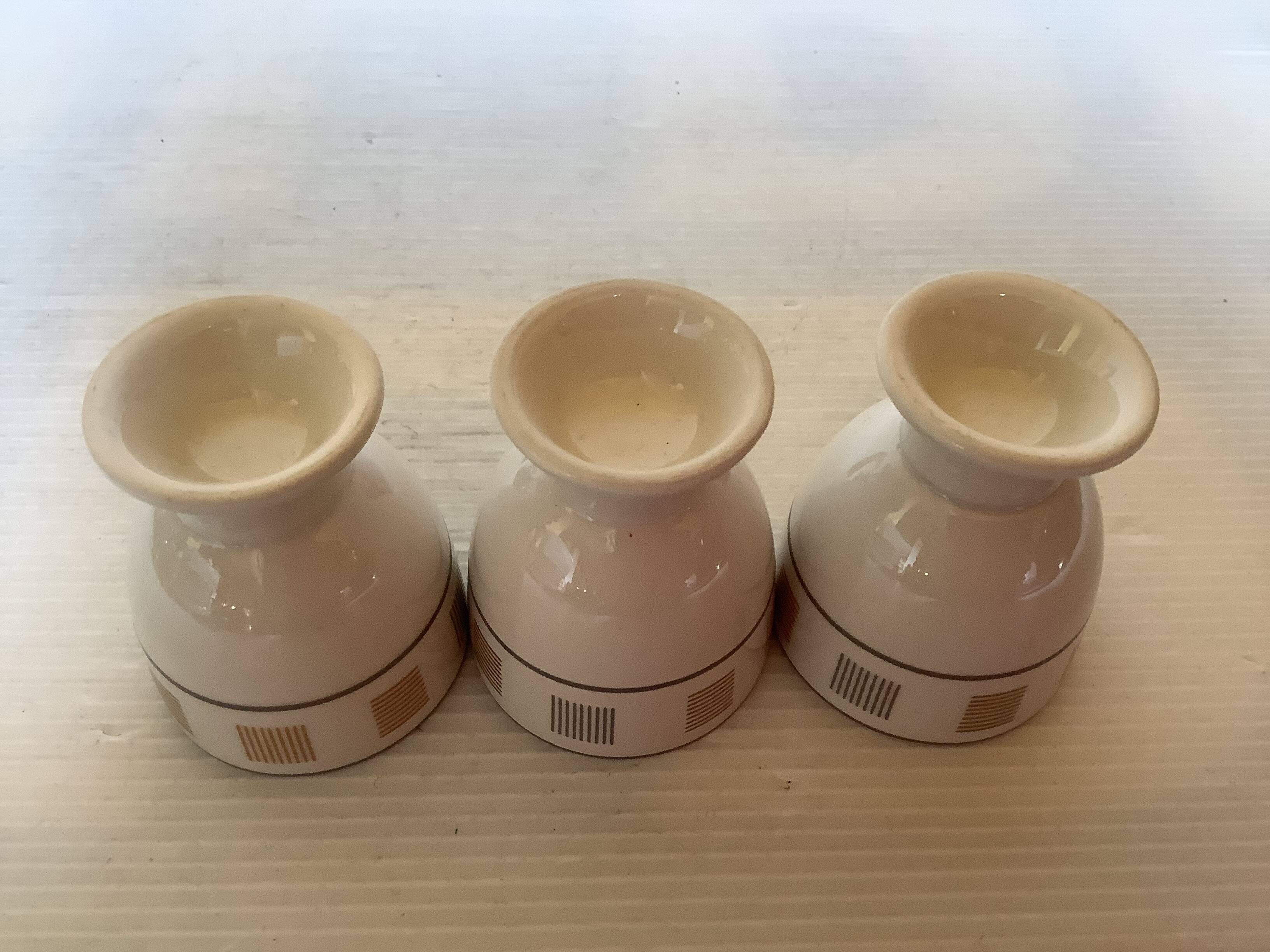 Three egg cups with geometric patterns in beige and brown.