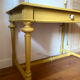 Desk table from the late 19th century, painted mustard, with turned stretcher.