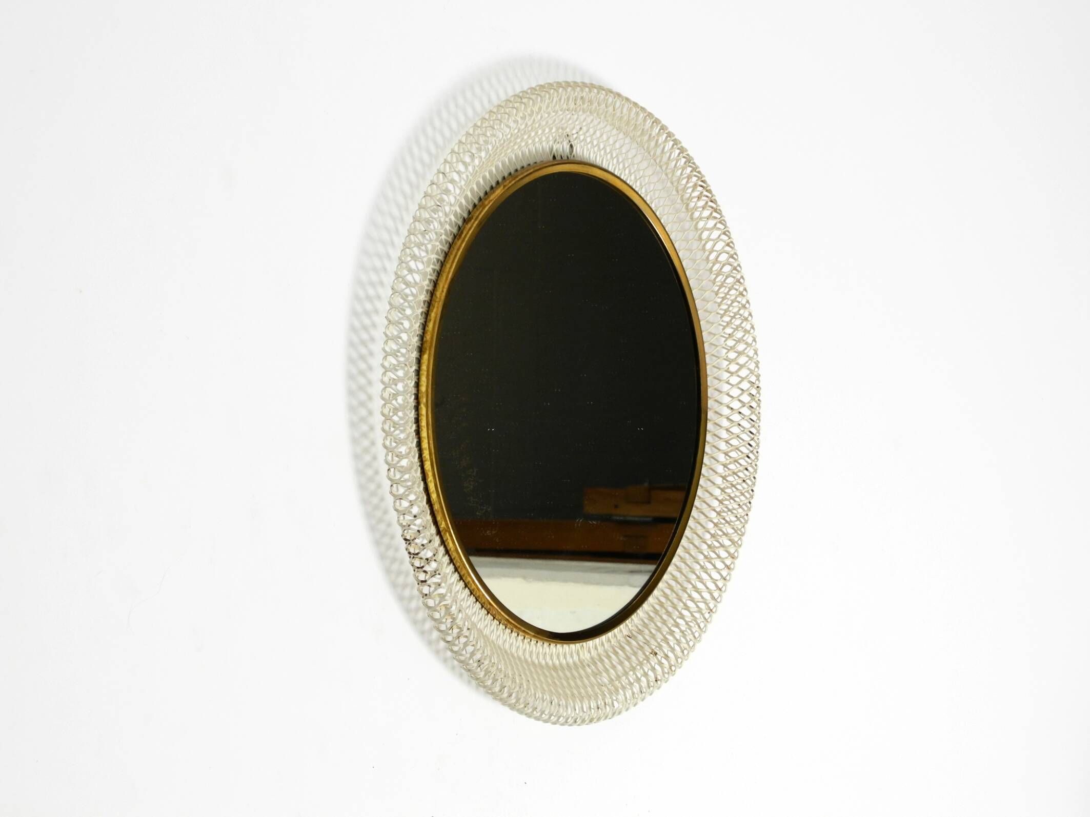 Mid Century Modern round wall mirror with a white expanded metal frame