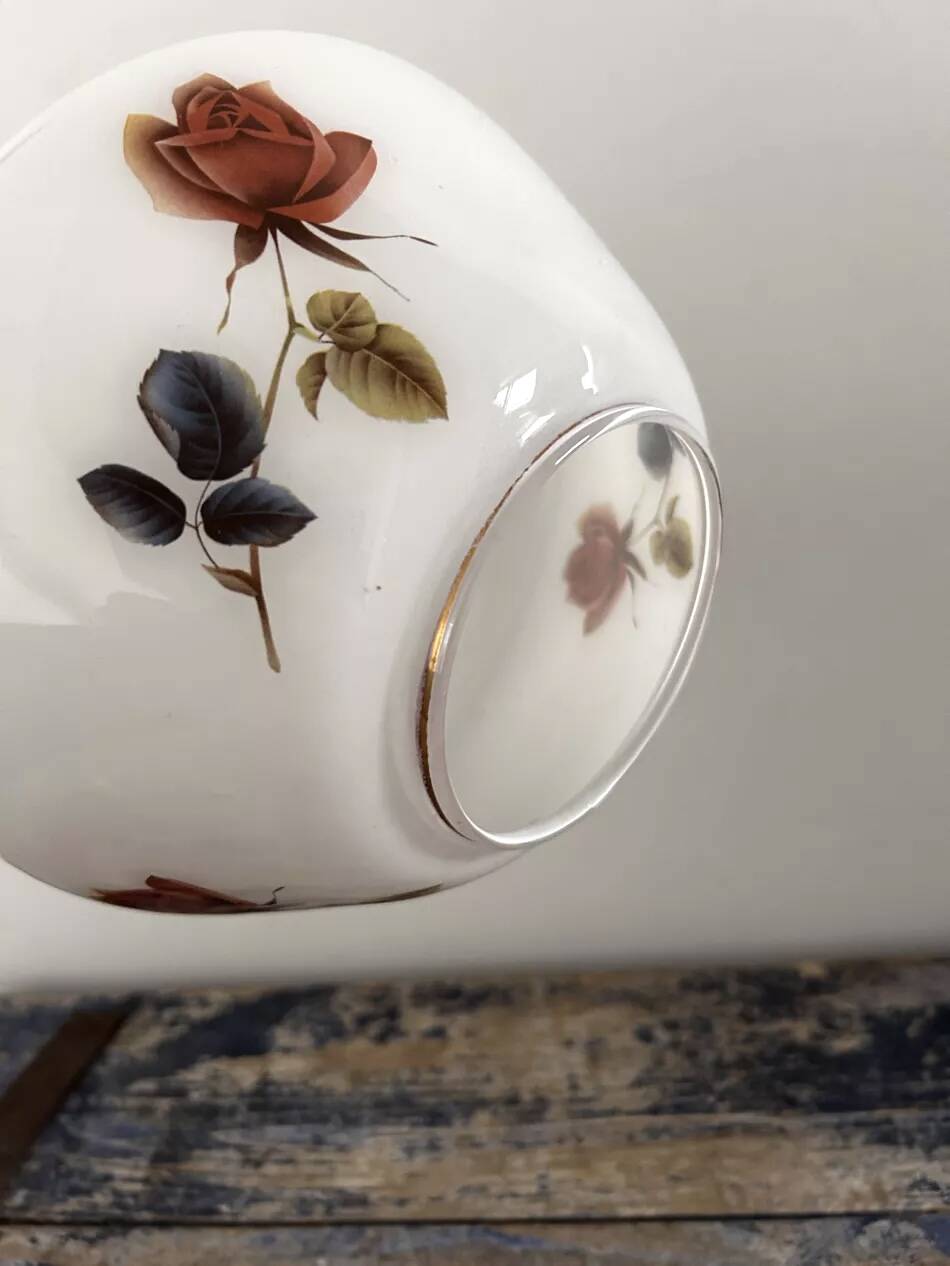 Golden tilting wall light with flowered globe