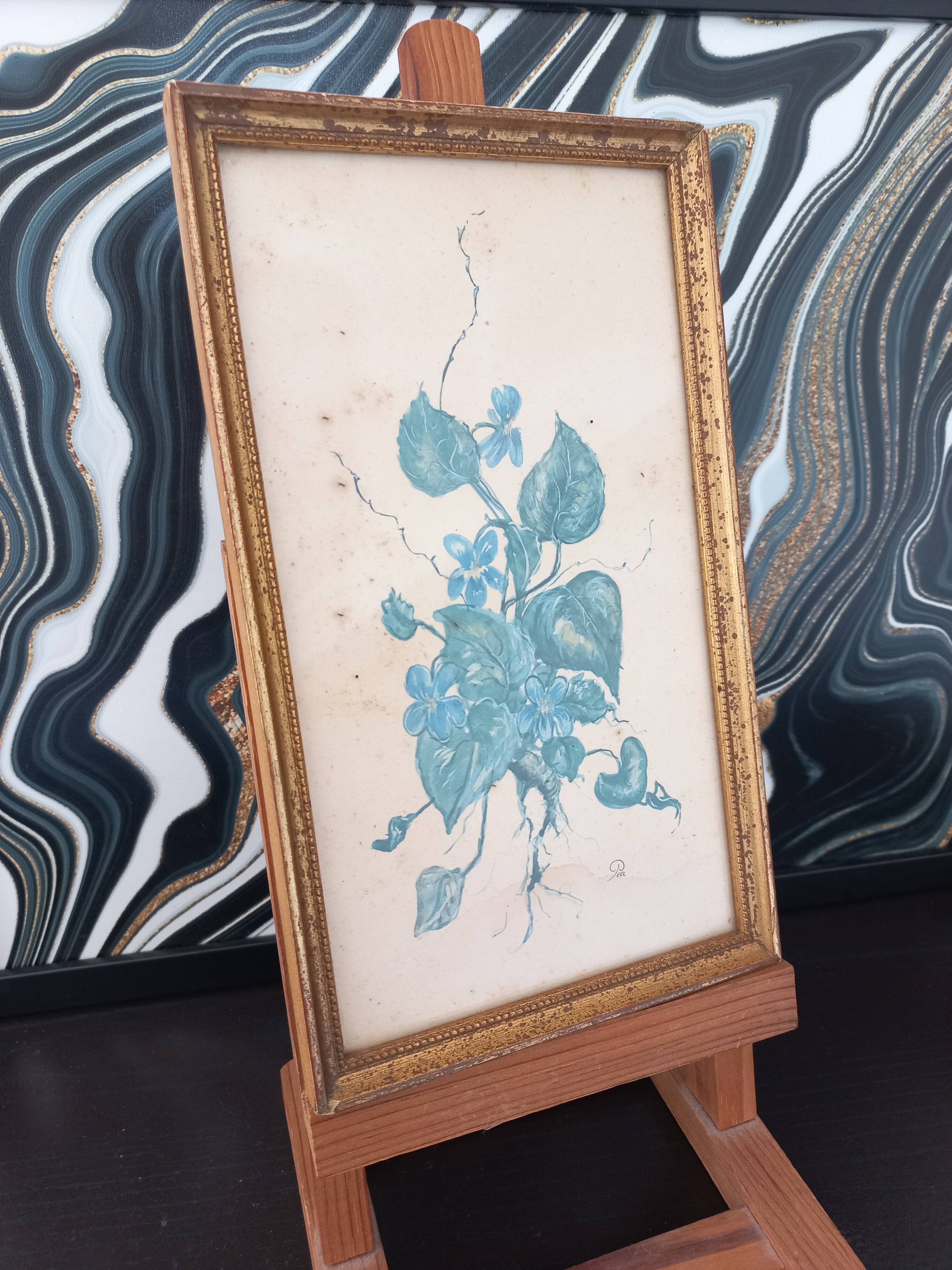Decorative table with vintage blue flowers in a golden frame.