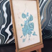 Decorative table with vintage blue flowers in a golden frame.