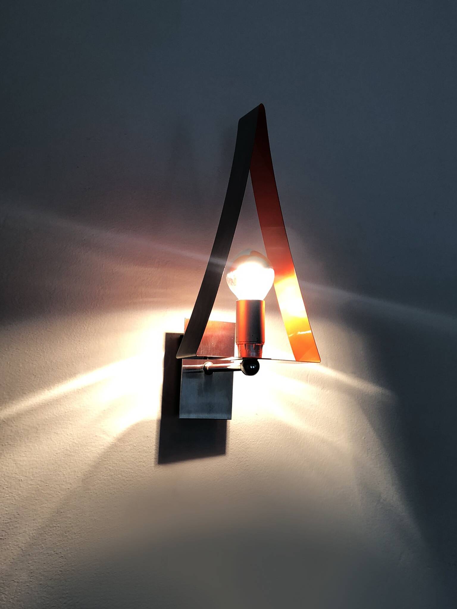 Pair of triangular wall sconces in chrome metal and orange. 1970s.