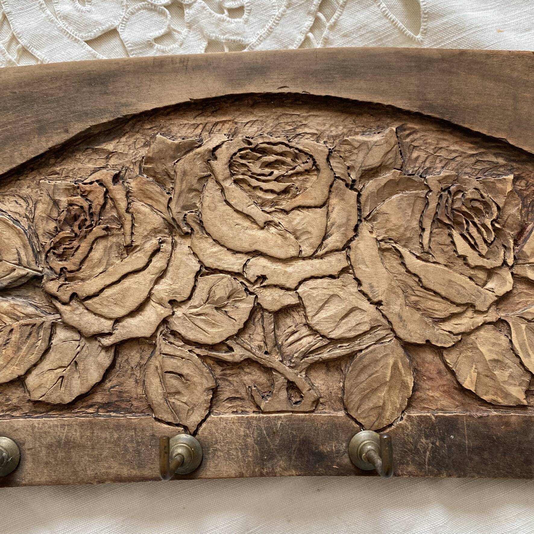Wall-mounted coat rack in carved wood with rose decoration.