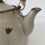 Beige stoneware teapot with stylized flowers and rattan handle