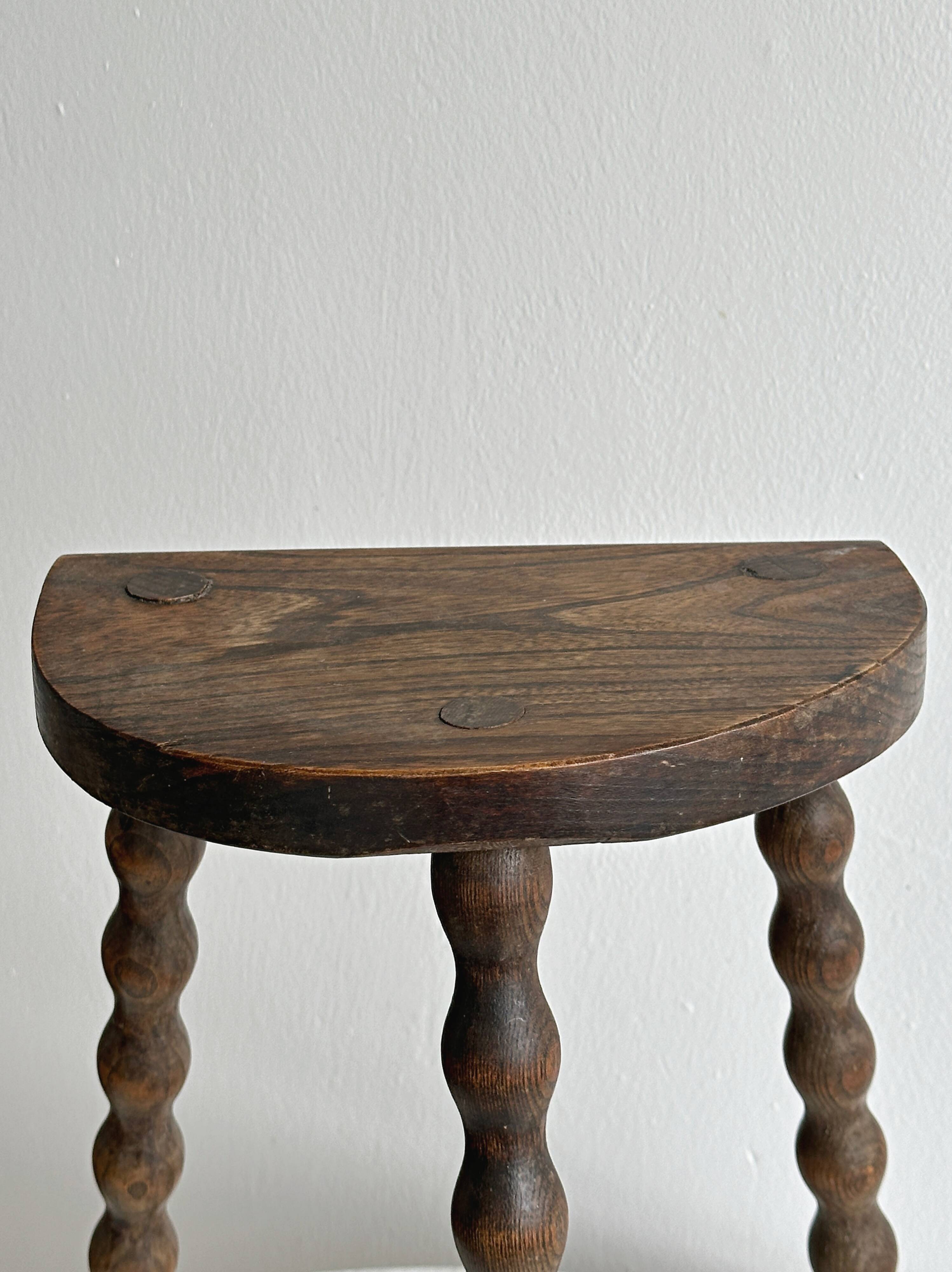 Three-legged demi-lune stool made of turned wood