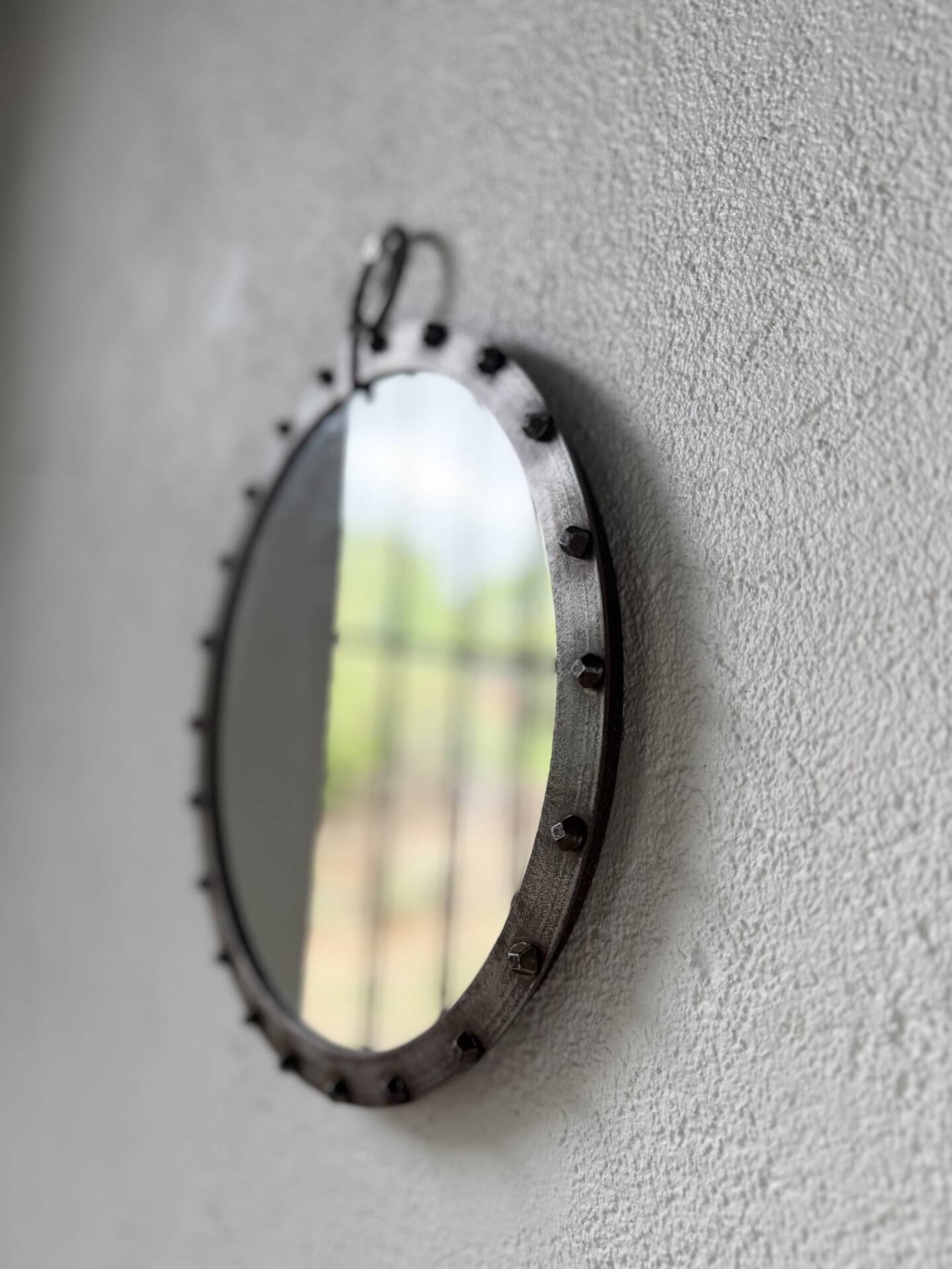 Brutalist round mirror with wrought iron and studs.