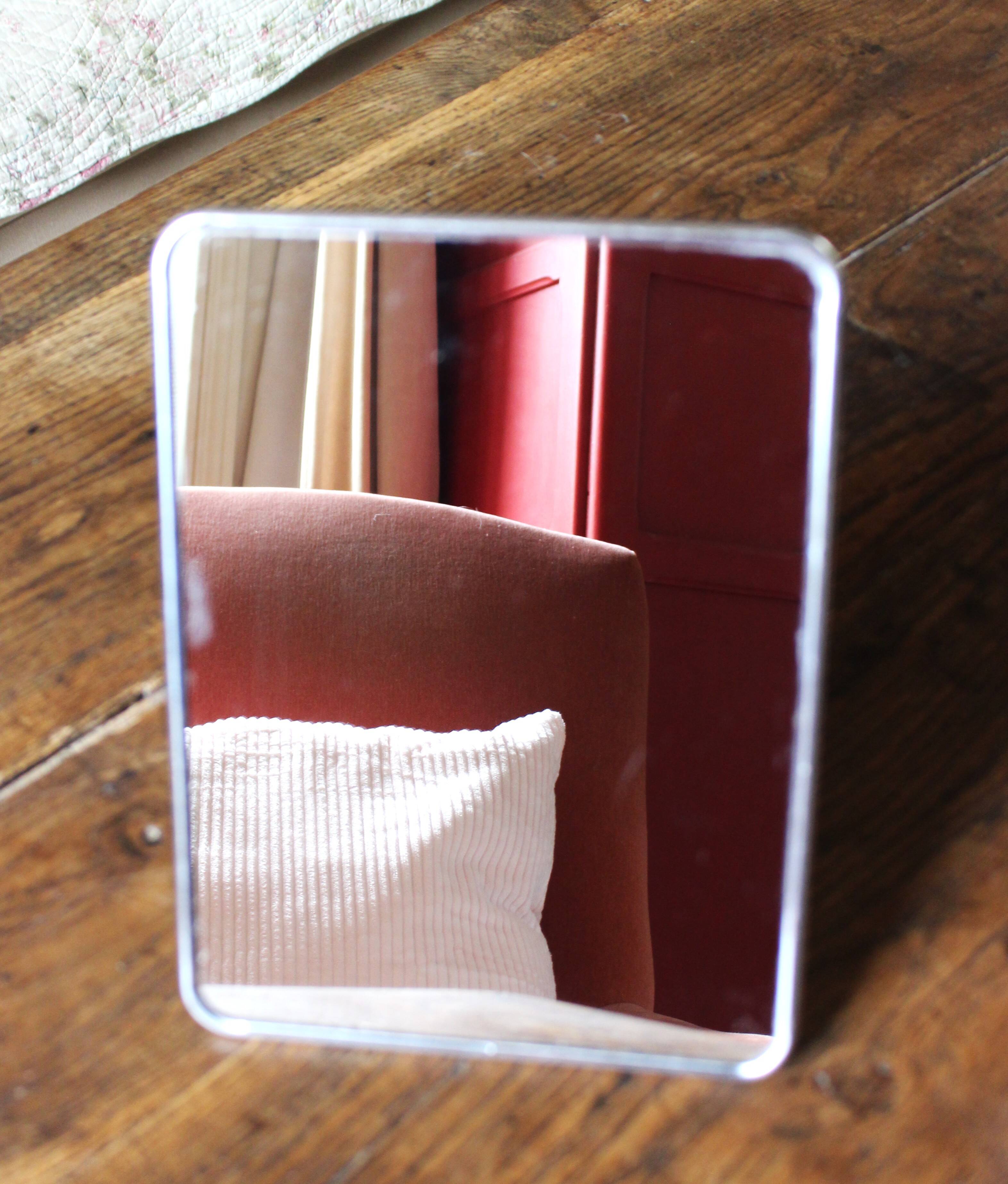 Simple rectangular barber mirror with a stand.