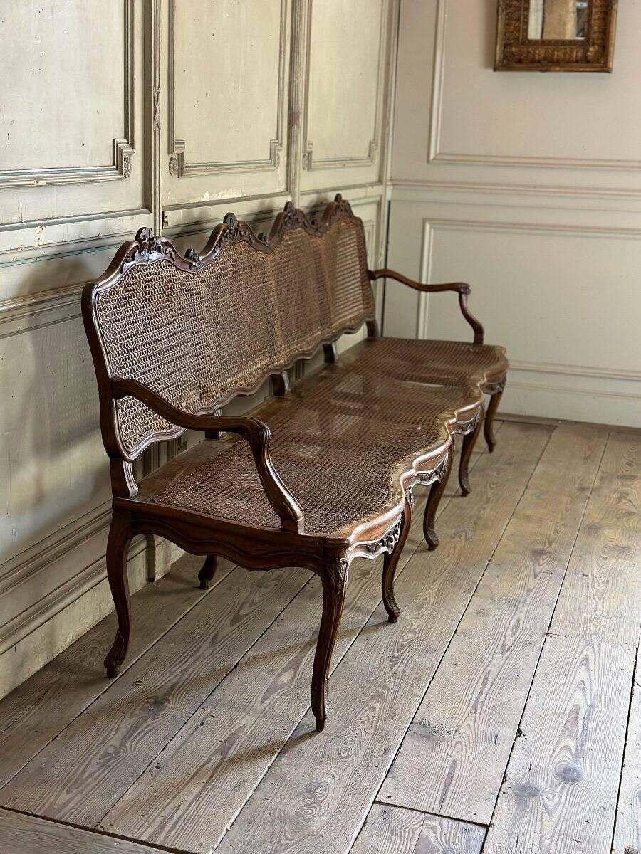 Grande banquette Louis XV en bois naturel mouluré et sculpté, France XVIIIème siècle