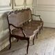 Grande banquette Louis XV en bois naturel mouluré et sculpté, France XVIIIème siècle
