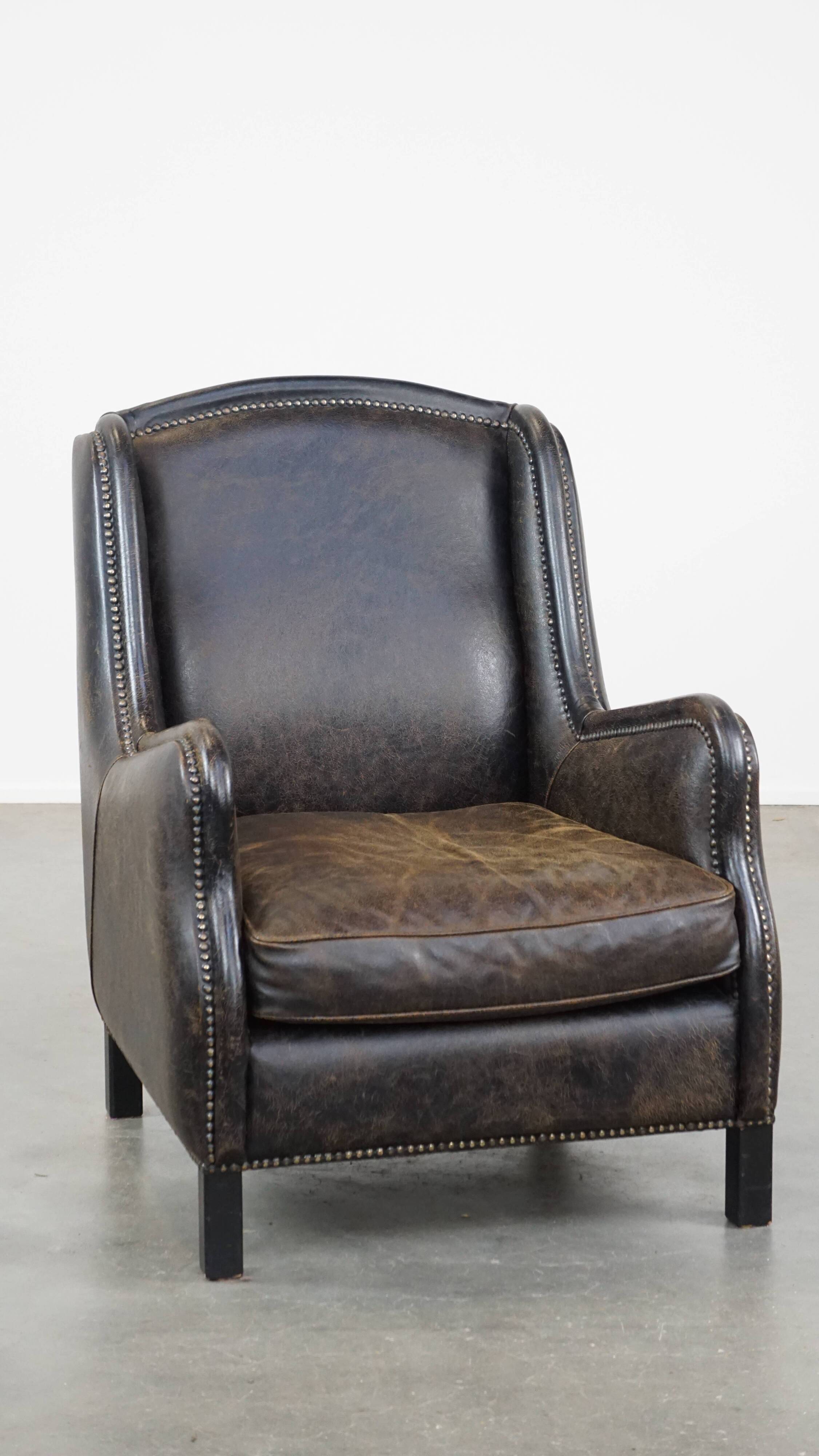 Black cow leather armchair finished with decorative nails, industrial style