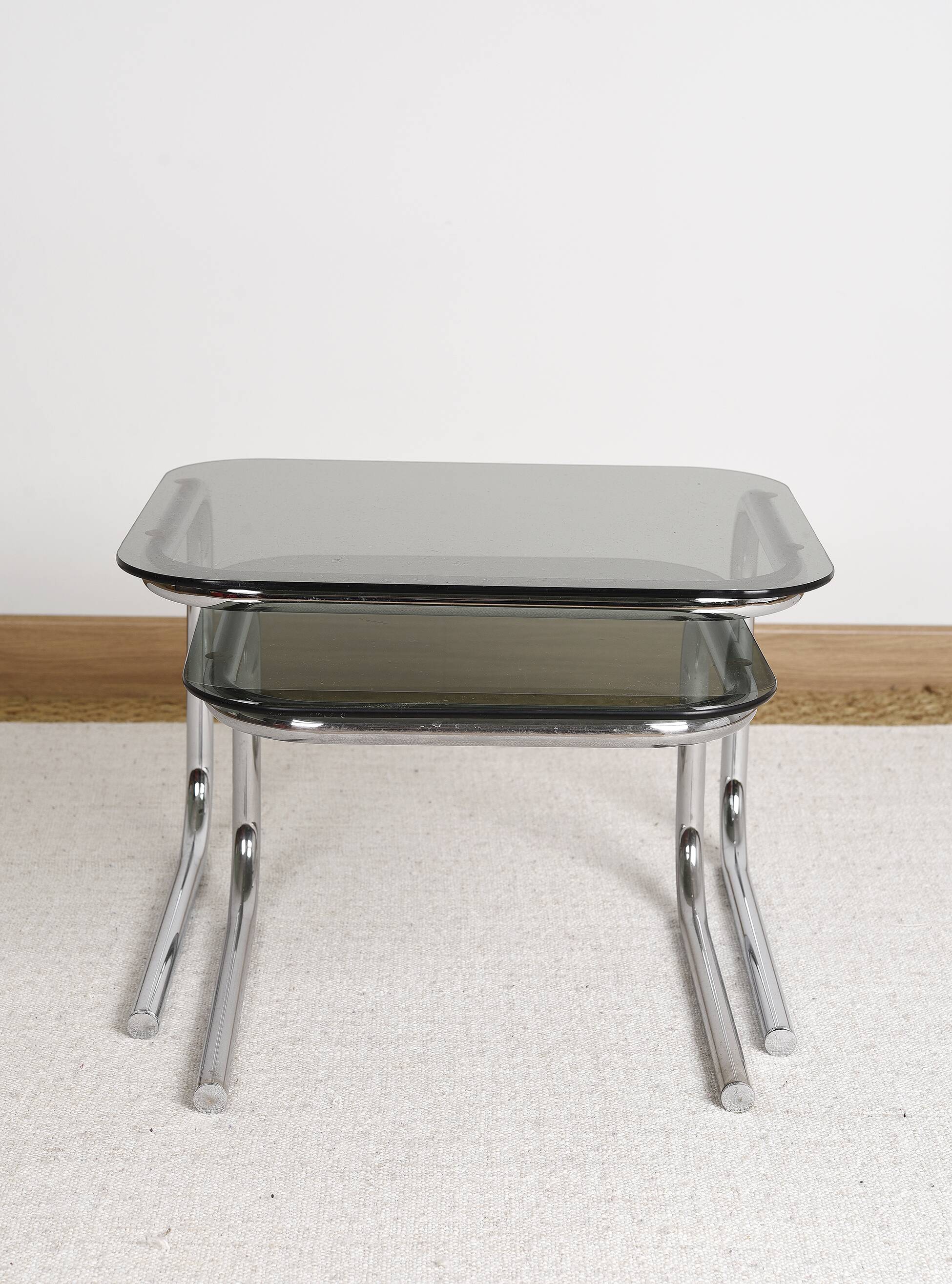 Pair of nesting tables in smoked glass and chrome legs.