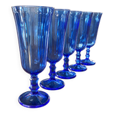 Set of 5 blue glass champagne flutes with faceted stems.