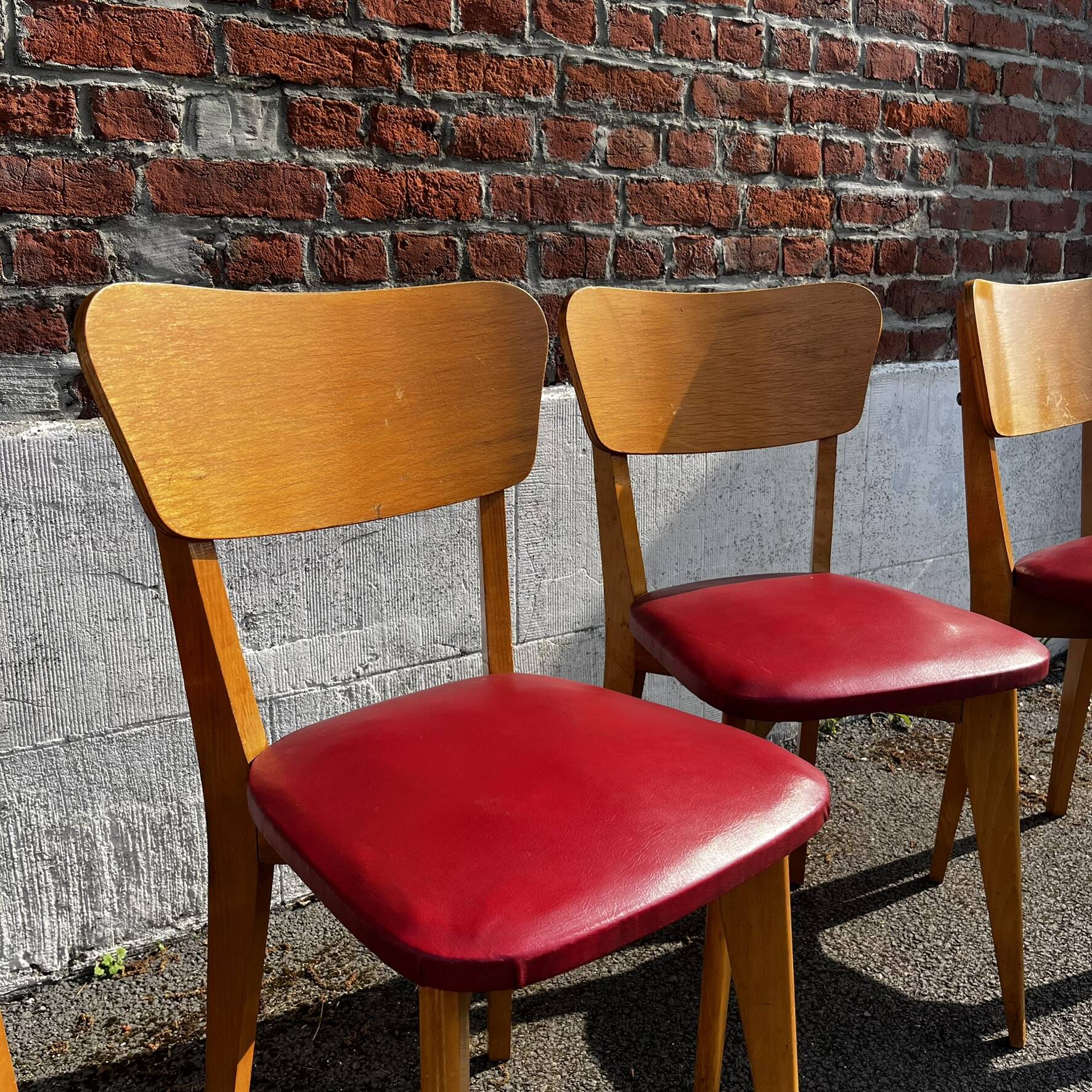 Set of 4 vintage bistro chairs in wood and red faux leather, with splayed legs.
