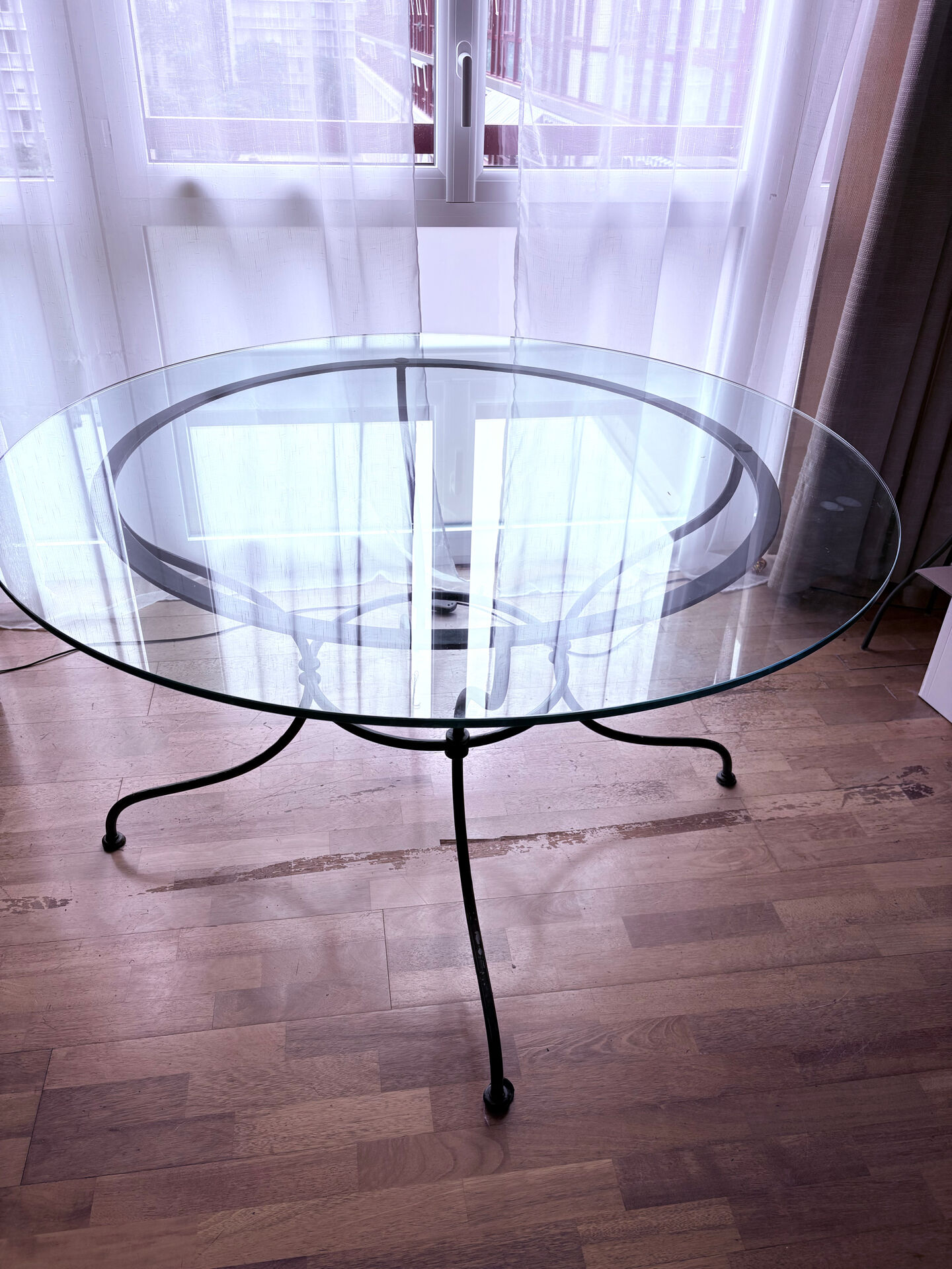 Round dining table in glass and wrought iron.