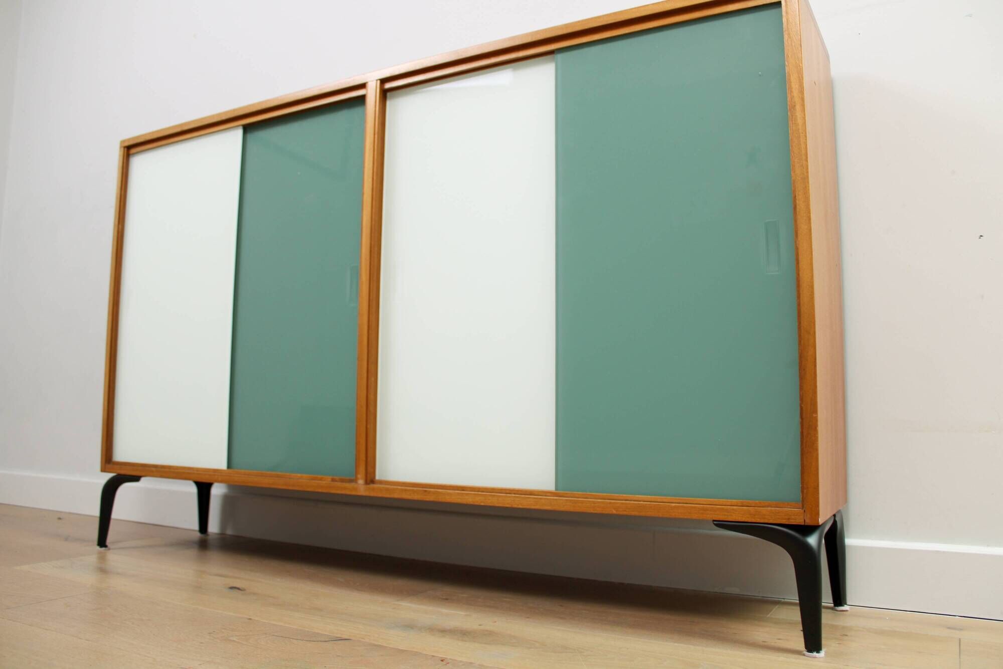 A vintage mid-century bookshelf/sideboard with green and white sliding door