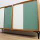 A vintage mid-century bookshelf/sideboard with green and white sliding door