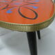 Plant holder tripod in geometrically patterned orange formica