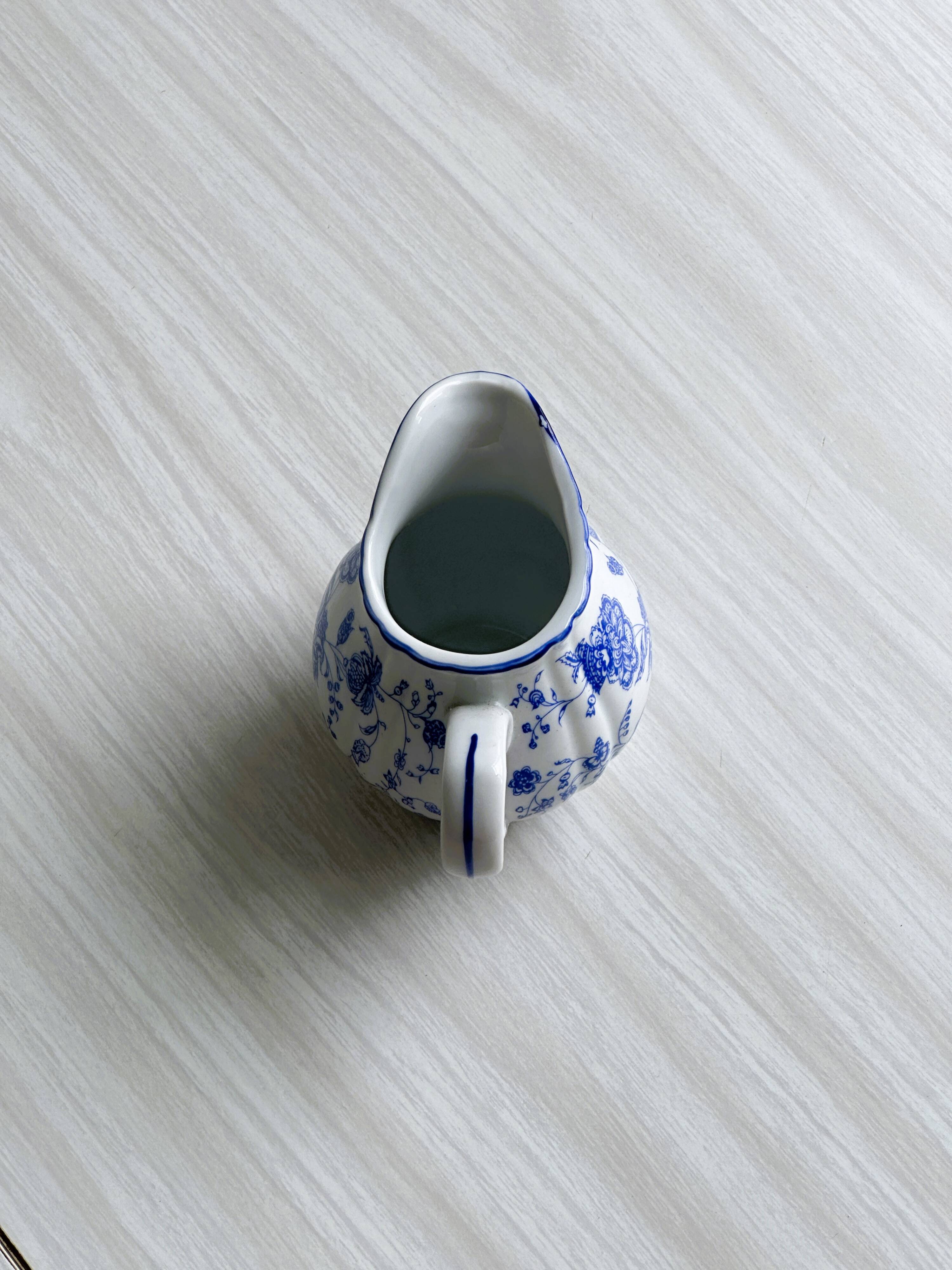 White porcelain milk jug with blue floral designs.